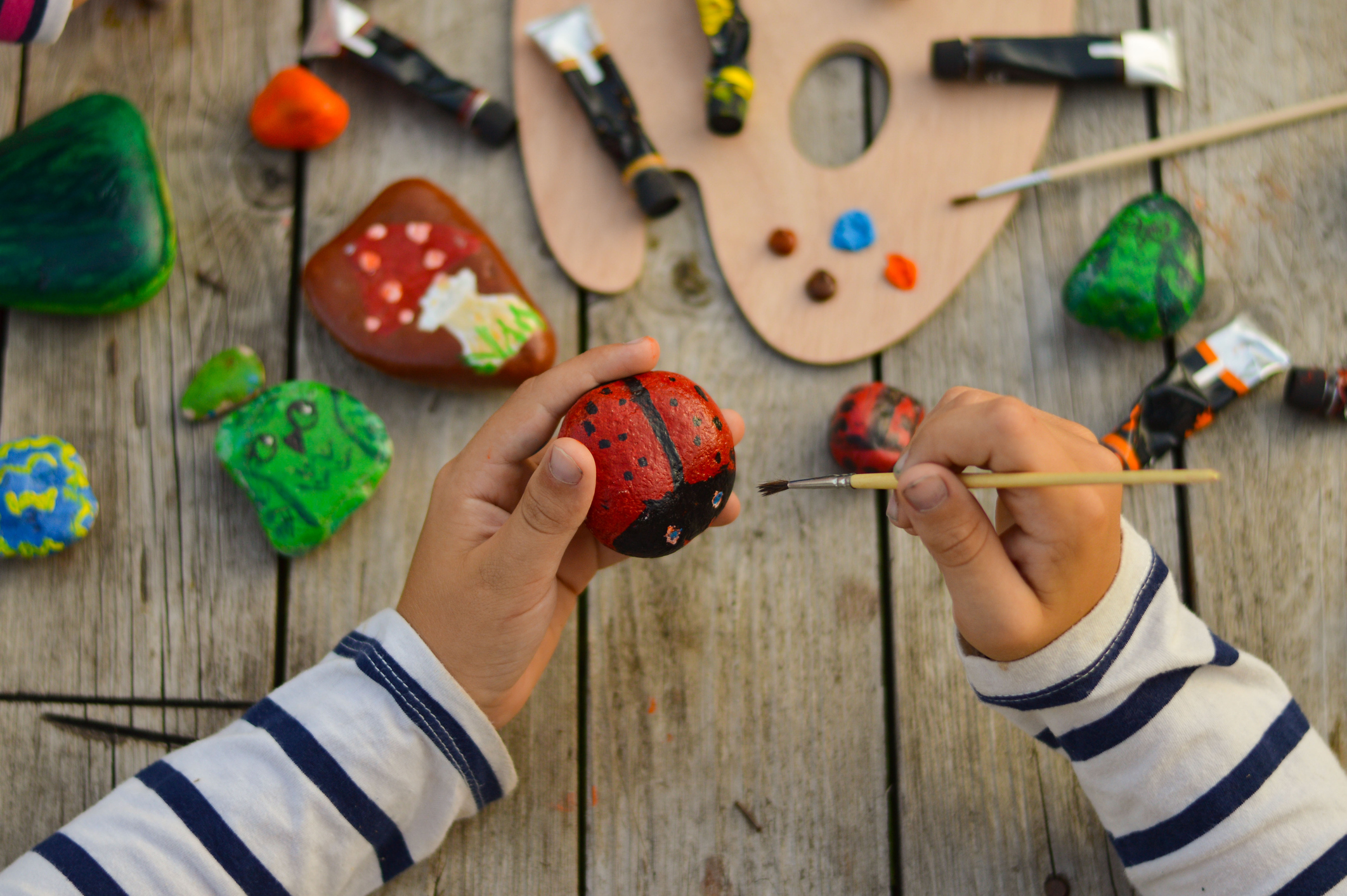 Besucherkinder bemalen Glückssteine als Gemeinschaftsritual für eine freie Willkommensfeier in Bonn.
